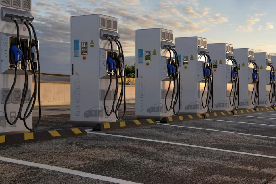 Row of white electric vehicle chargers in an outdoor parking lot.